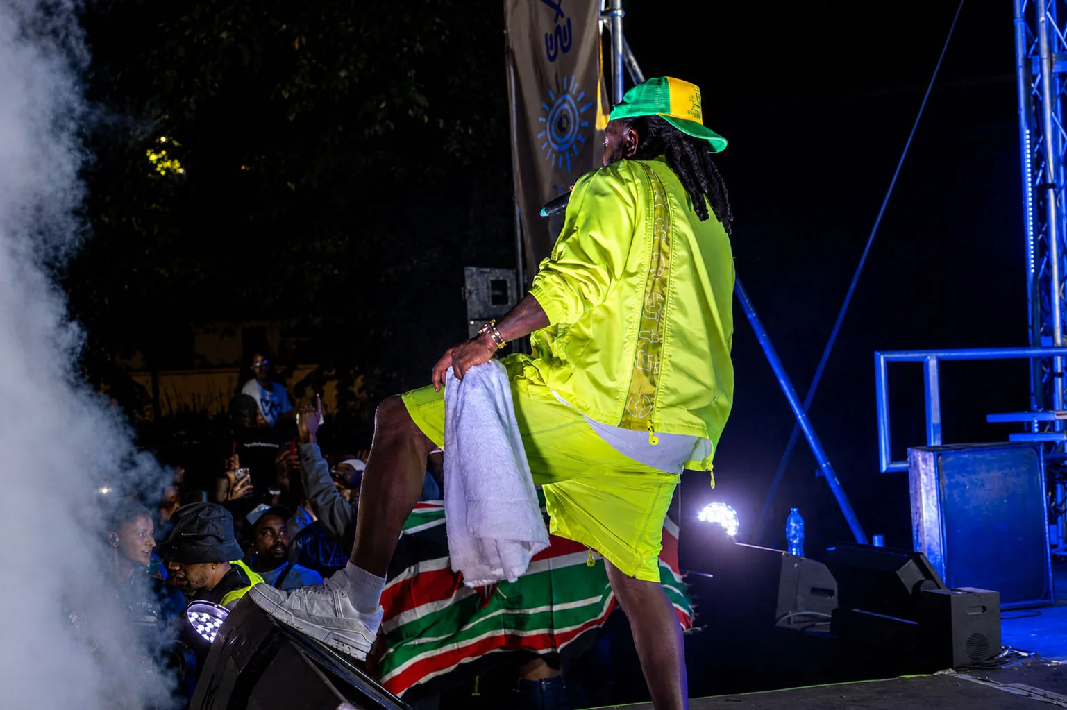 Timaya facing the crowd with a Zimbabwe flag draped on the barrier