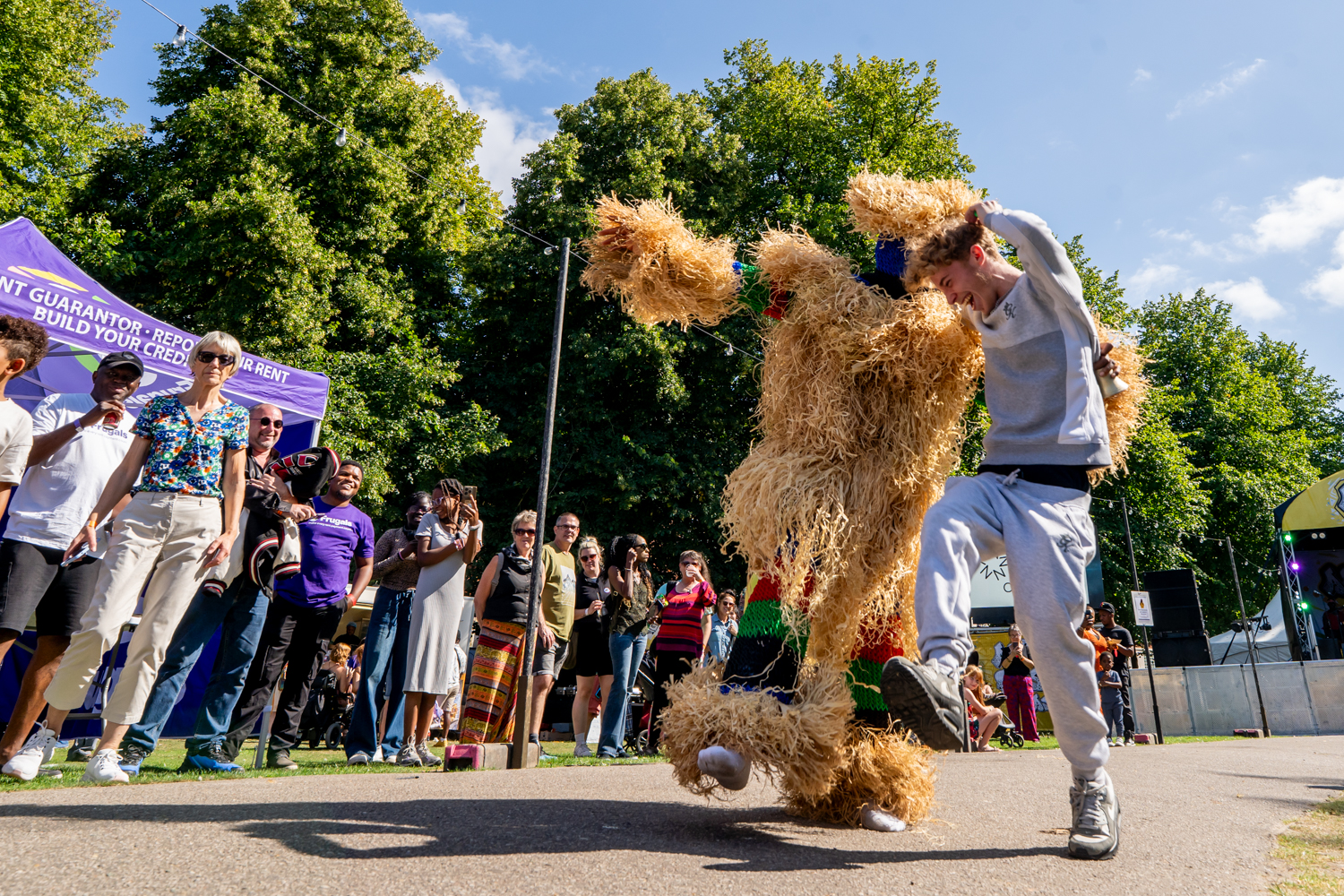 A costumed performer dancing in front of a festival crowd at Afri-Fest East