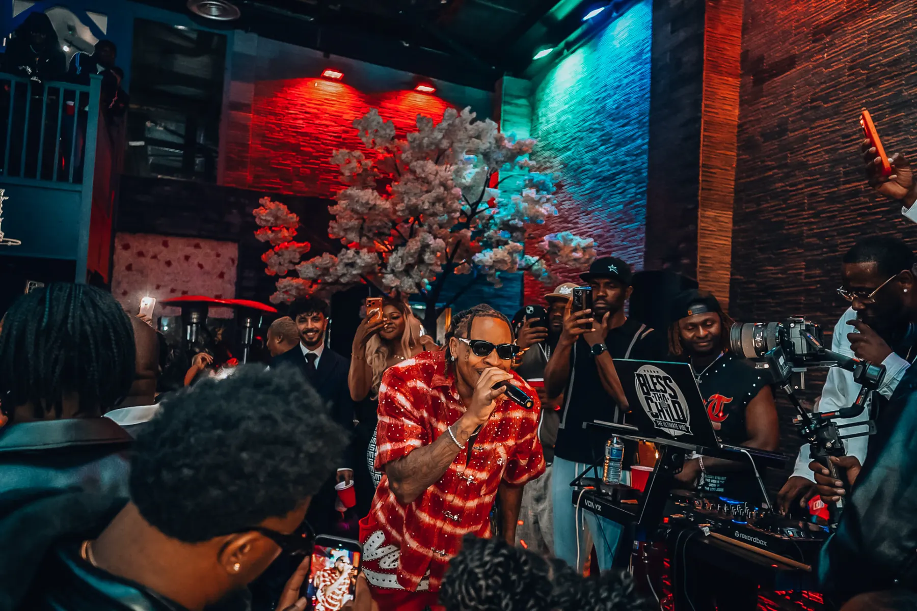 Rotimi on the microphone with phones raised around him