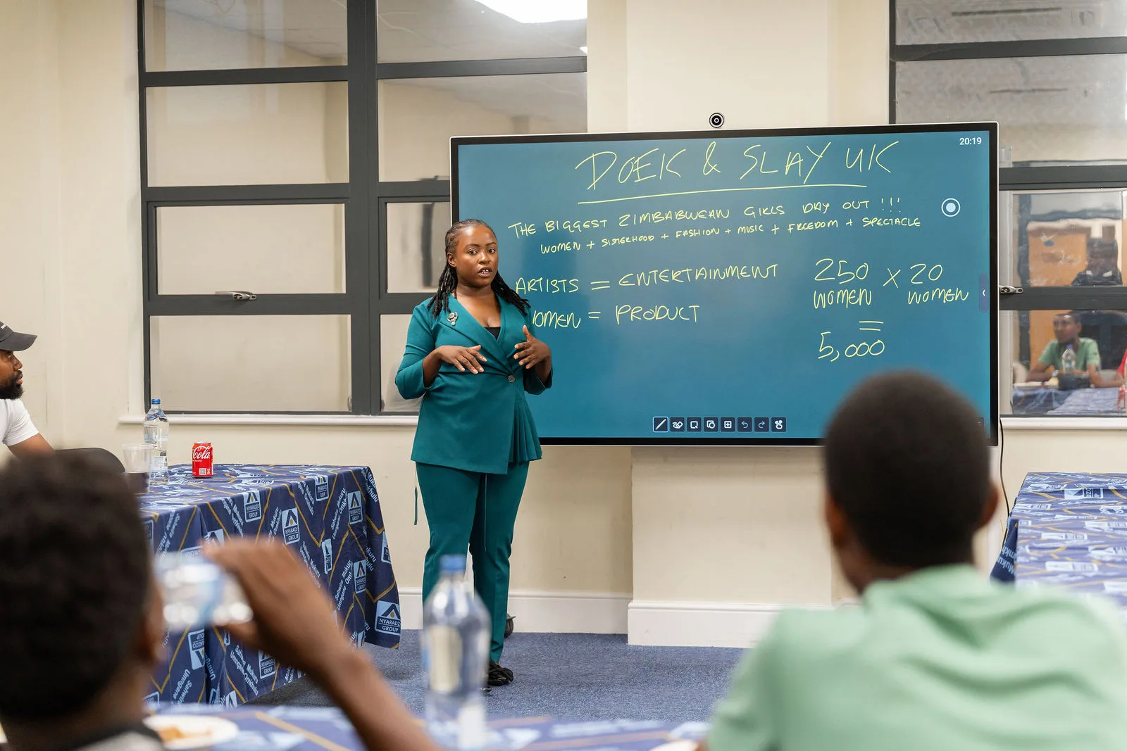 Korrine Sky in a green suit presenting the Doek & Slay UK strategy board at Nyaradzo House