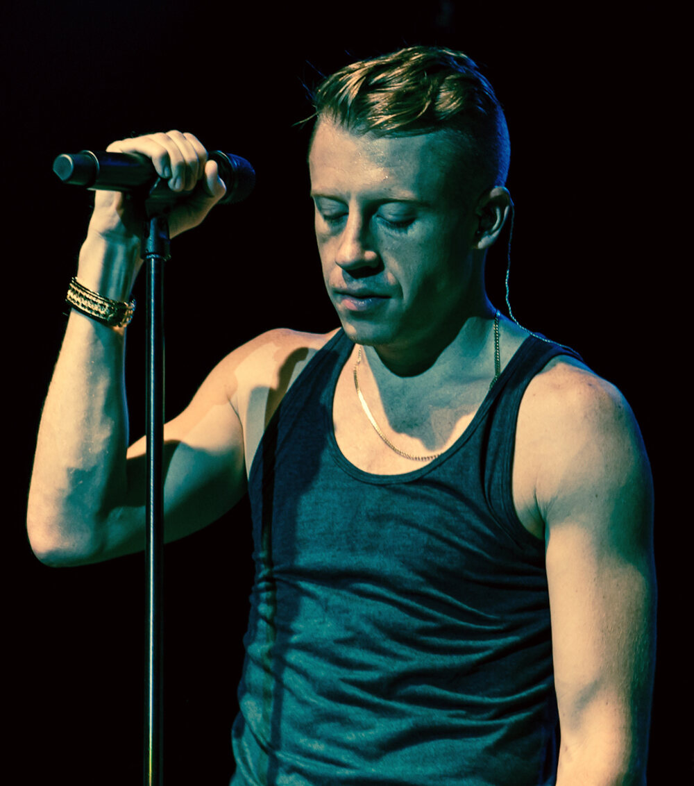 Macklemore performing on stage with a microphone